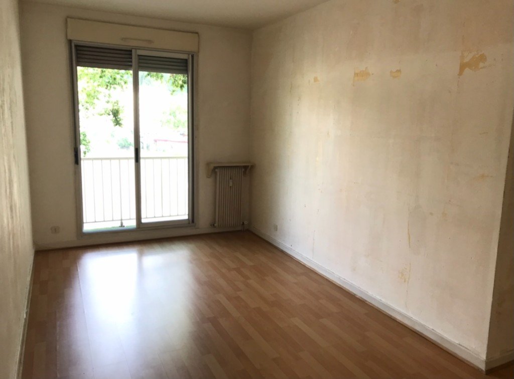 Chambre vide avant mise en scène : murs marqués, sol seul et baie vers le balcon.