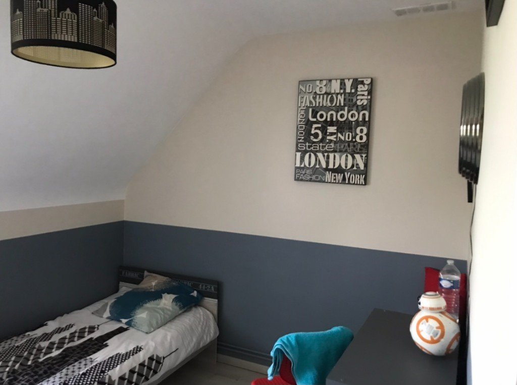 Chambre sous combles avant réorganisation : murs bicolores, lit et bureau sous la pente.