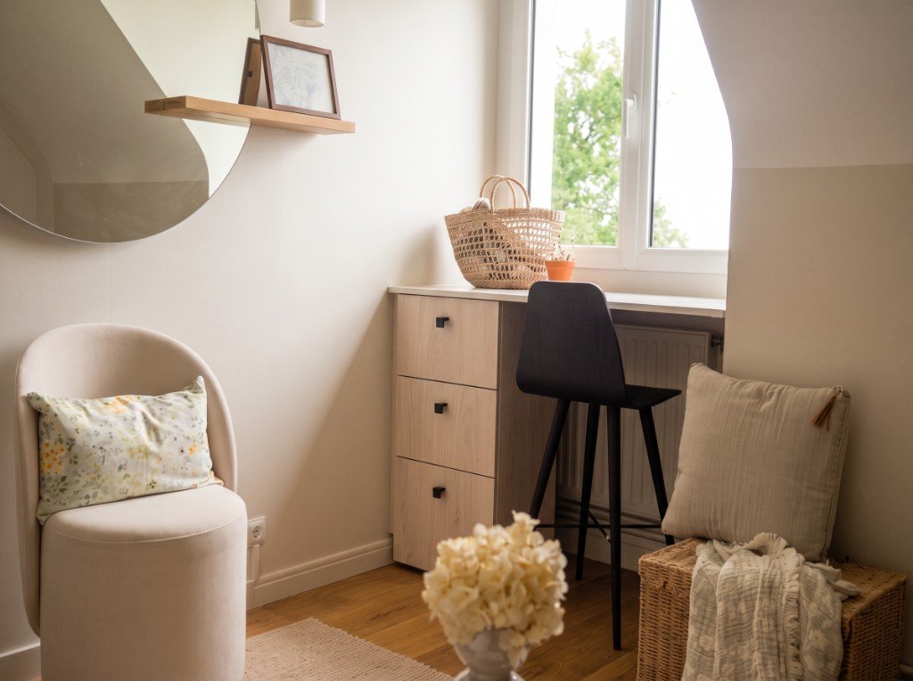 Coin bureau après aménagement : miroir rond, fauteuil crème, bureau clair et panier en osier.